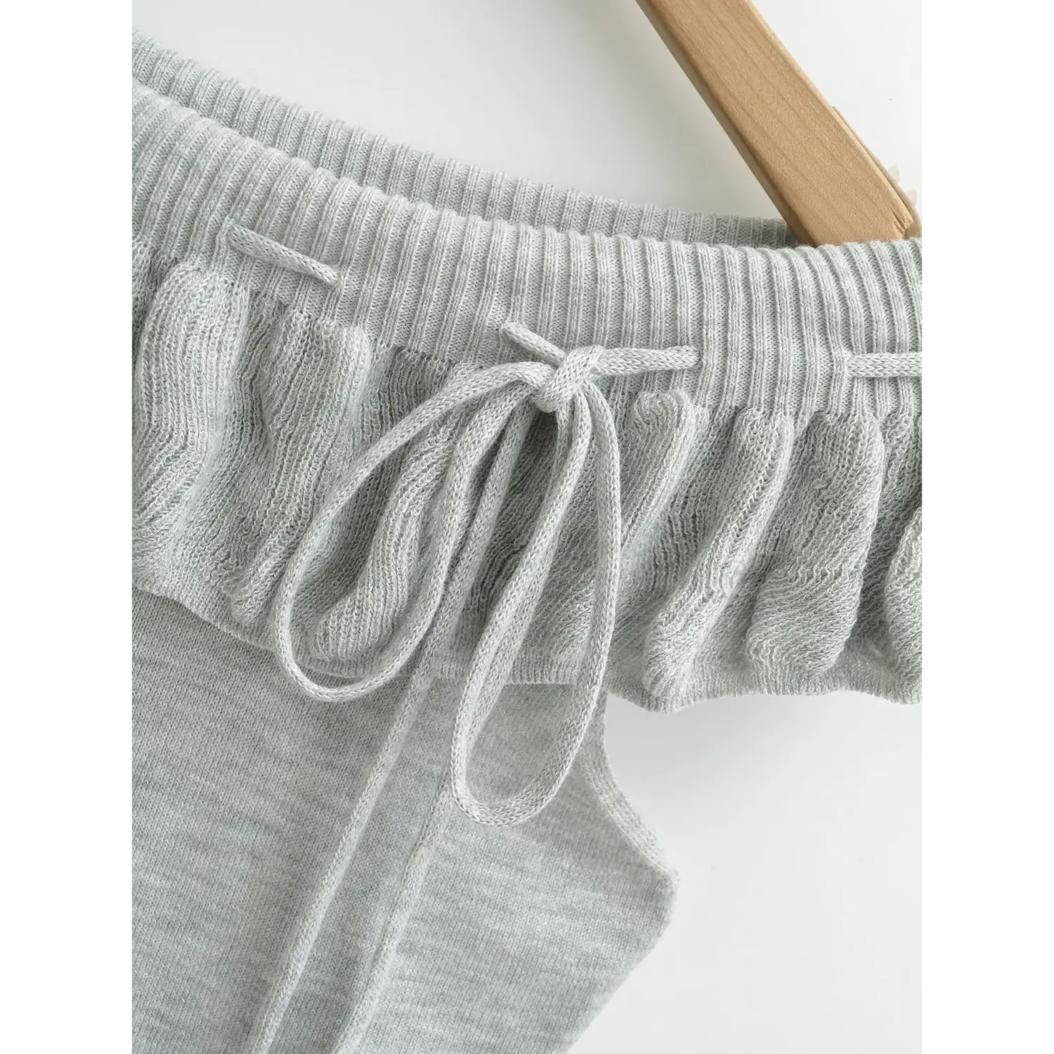Front drawstring tie ruffle knit tube top macro flat close-up, matching fabric thin drawstring stitched loops flounce neck gather stretch knit white background shot