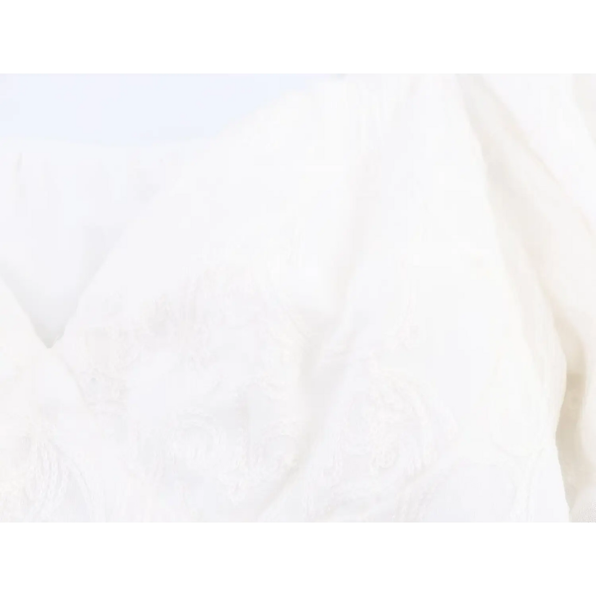 Detailed shot of front paisley embossed pattern on white long sleeve cropped top