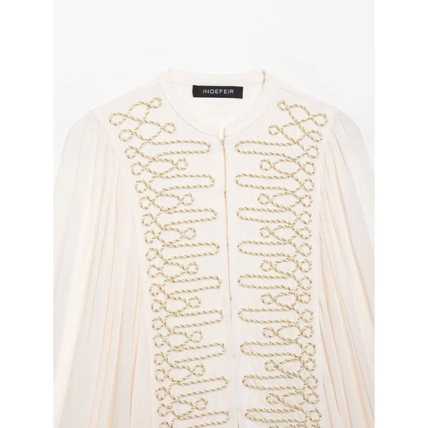 Chest close‑up, ornate gold cord loop embroidery on white stand‑collar cropped blouse