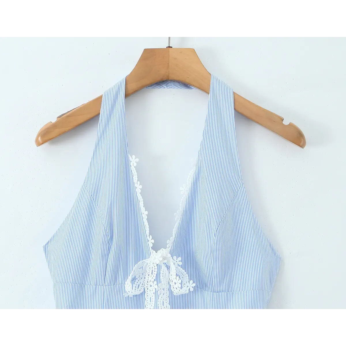 Close-up of the front halter neckline on a blue and white striped dress, highlighting the lace-trimmed V-neck and tie.