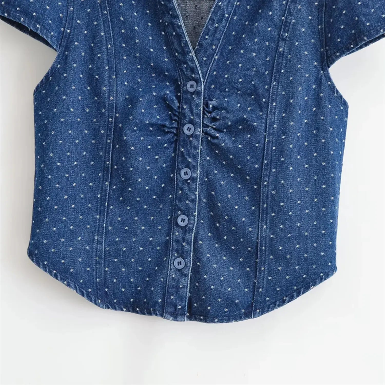 Mid-front partial shot, vertical button placket, four round denim buttons, bilateral fabric ruching at bust, tiny uniform white pinstripe dots