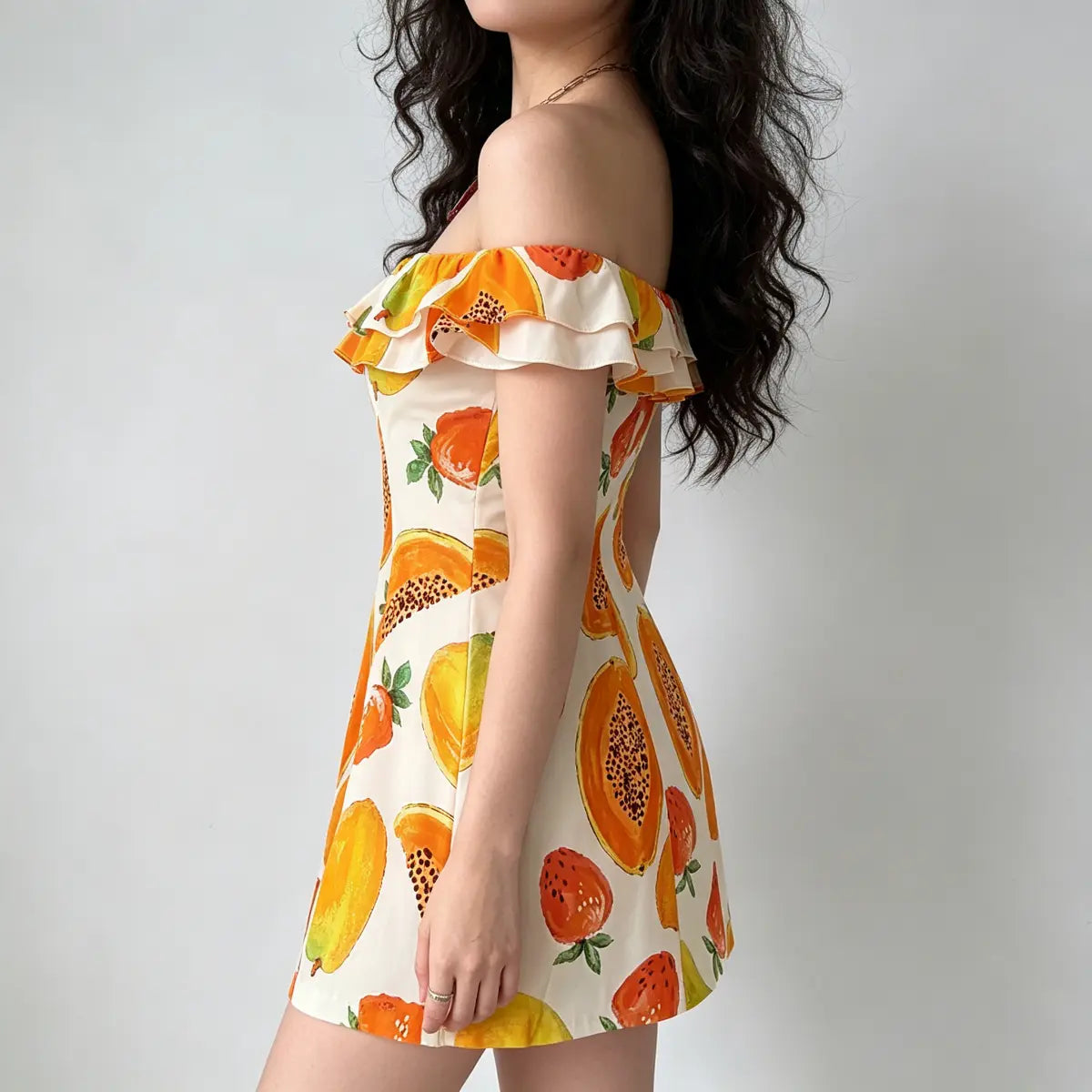Side view of off-shoulder fruit print dress, highlighting the A-line silhouette and ruffled neckline detail.