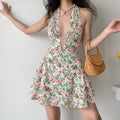 Model daily shot of off-white floral halter mini dress, deep plunge V neck + midriff cutout, fitted corset waist, flared ruffle skirt, styled with pearl heart pendant necklace & rattan handbag, summer vacation sweet sexy outfit