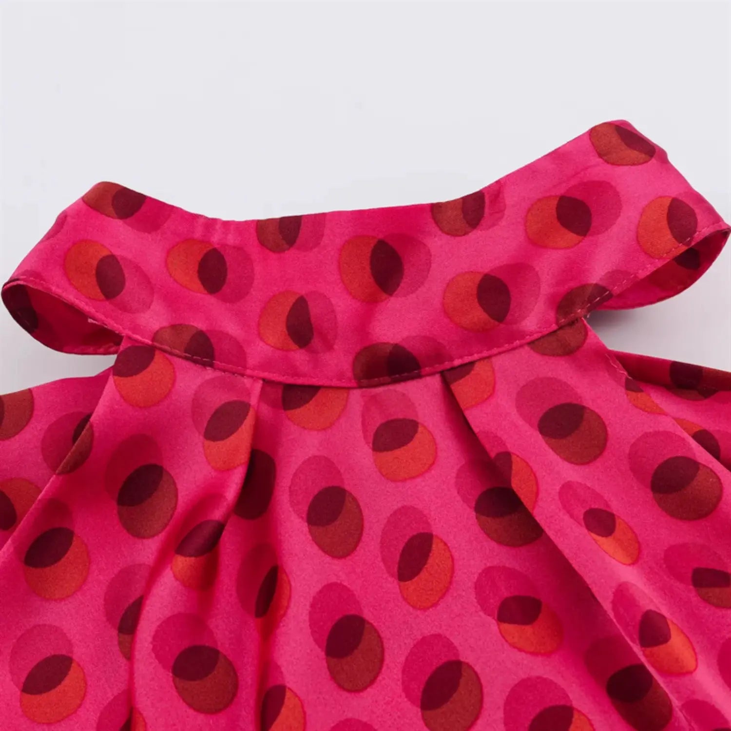 Halter stand collar edge stitching close-up, folded fabric binding, uniform polka dot print layout