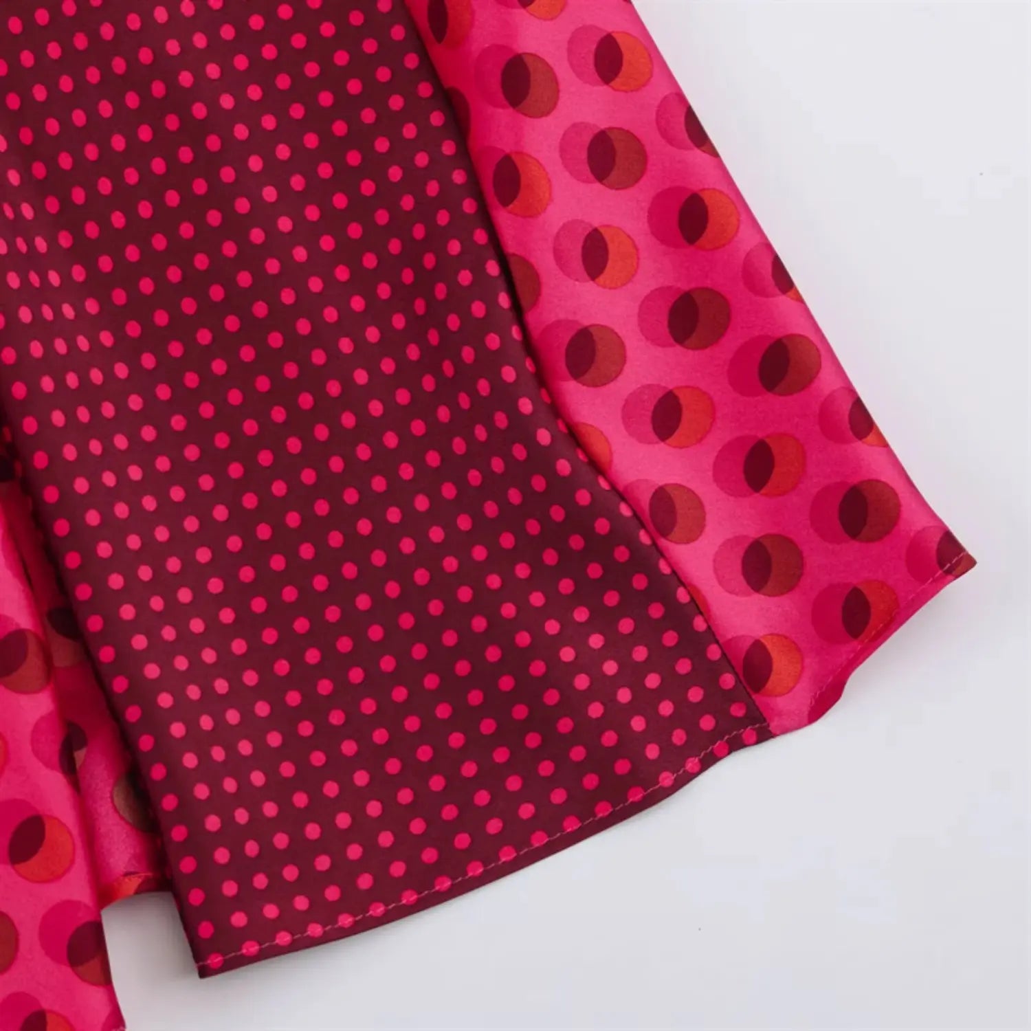 Side slit hem close-up, contrast two print satin fabric, outer large overlapping circle dots, inner dark tiny polka dot lining, neat straight hem overlock stitching