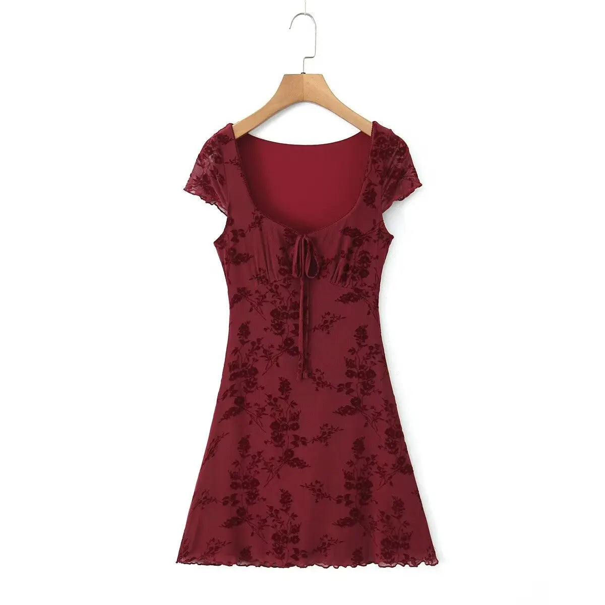 Full front view of a burgundy flocked floral mesh mini dress on a wooden hanger, featuring a square neckline with a front tie, cap sleeves, and flowy A-line hem.