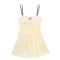 Full front view of a cream smocked cami mini dress, featuring black contrast straps, a small bow, tiered smocked bodice, and flowy skirt.