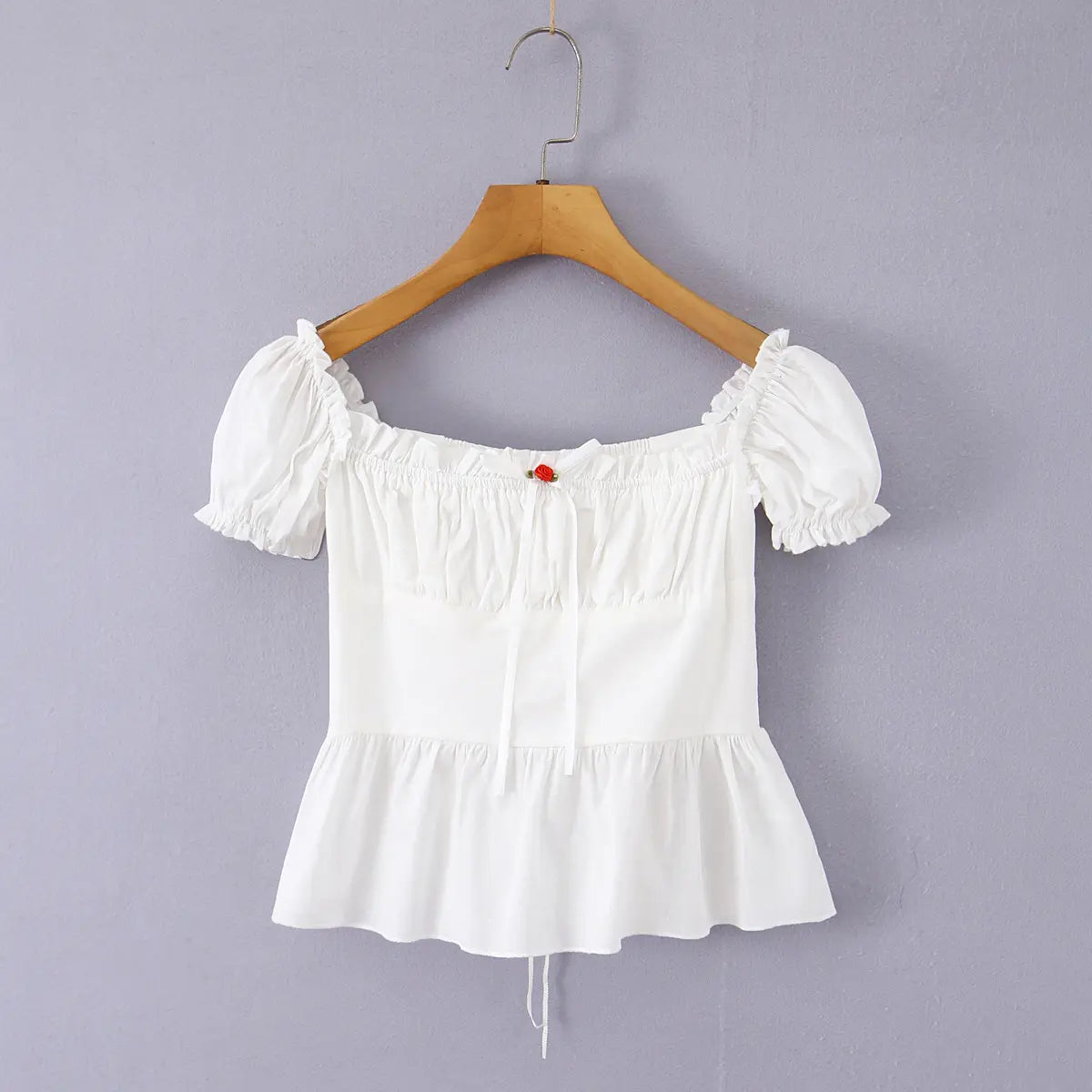 Close-up of the puff sleeve on a white off-shoulder peplum top, showing the ruffled elasticated edge and gathered construction.