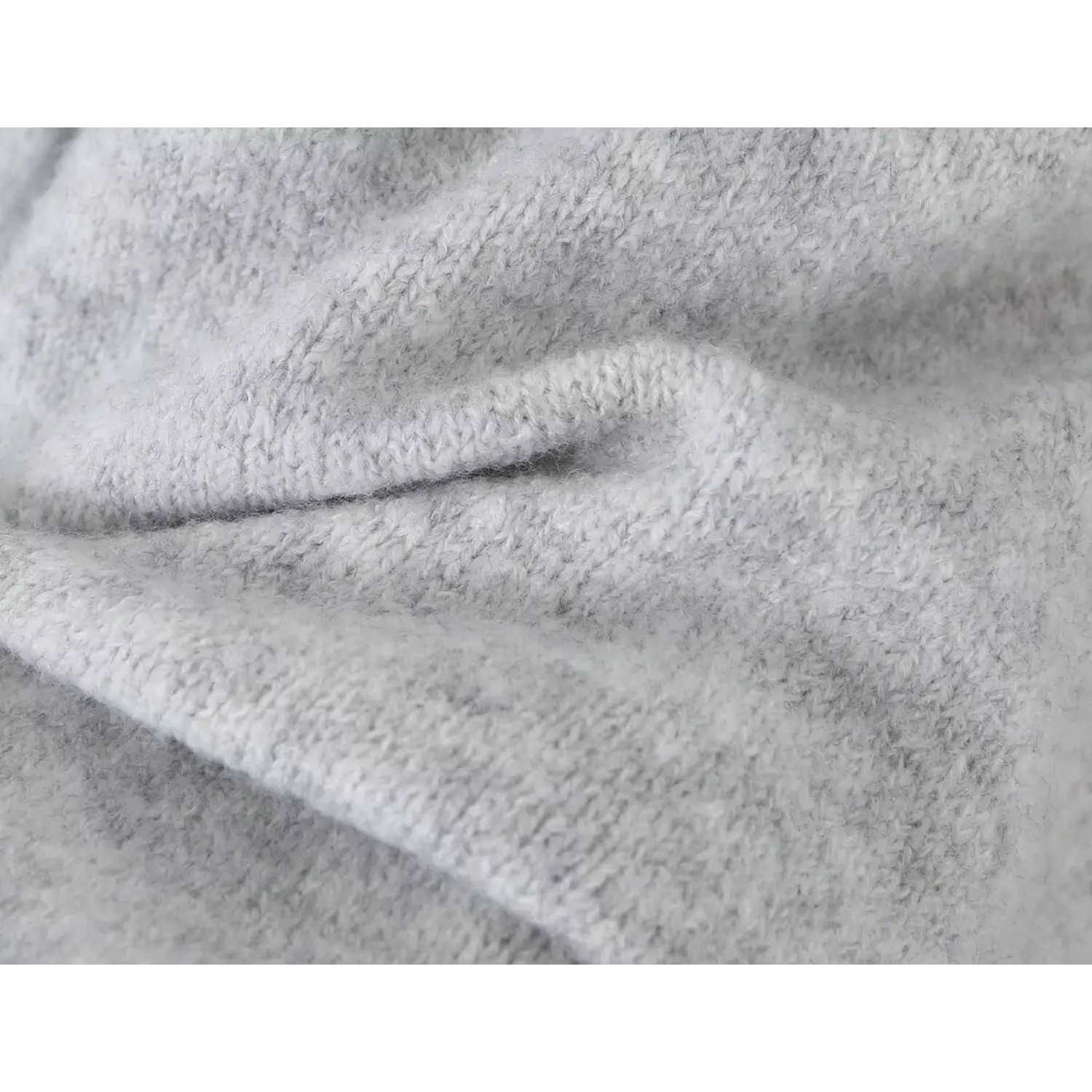 Close up folded wrinkle texture of fuzzy warm heather grey knit sweater dress material