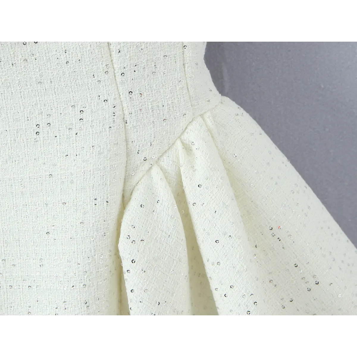Waist seam close, gathered transition into voluminous A-line mini skirt, speckled sequin woven tweed material.