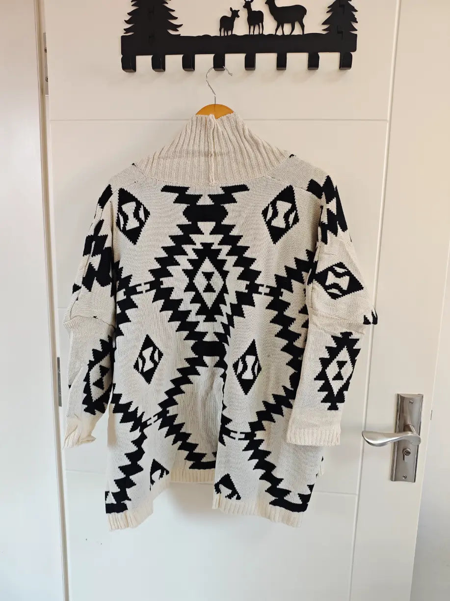 Geometric diamond intarsia open front cardigan hanging on door, back view