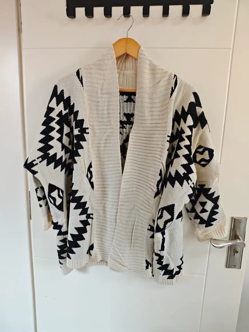 Geometric diamond intarsia open front cardigan hanging on door, front view