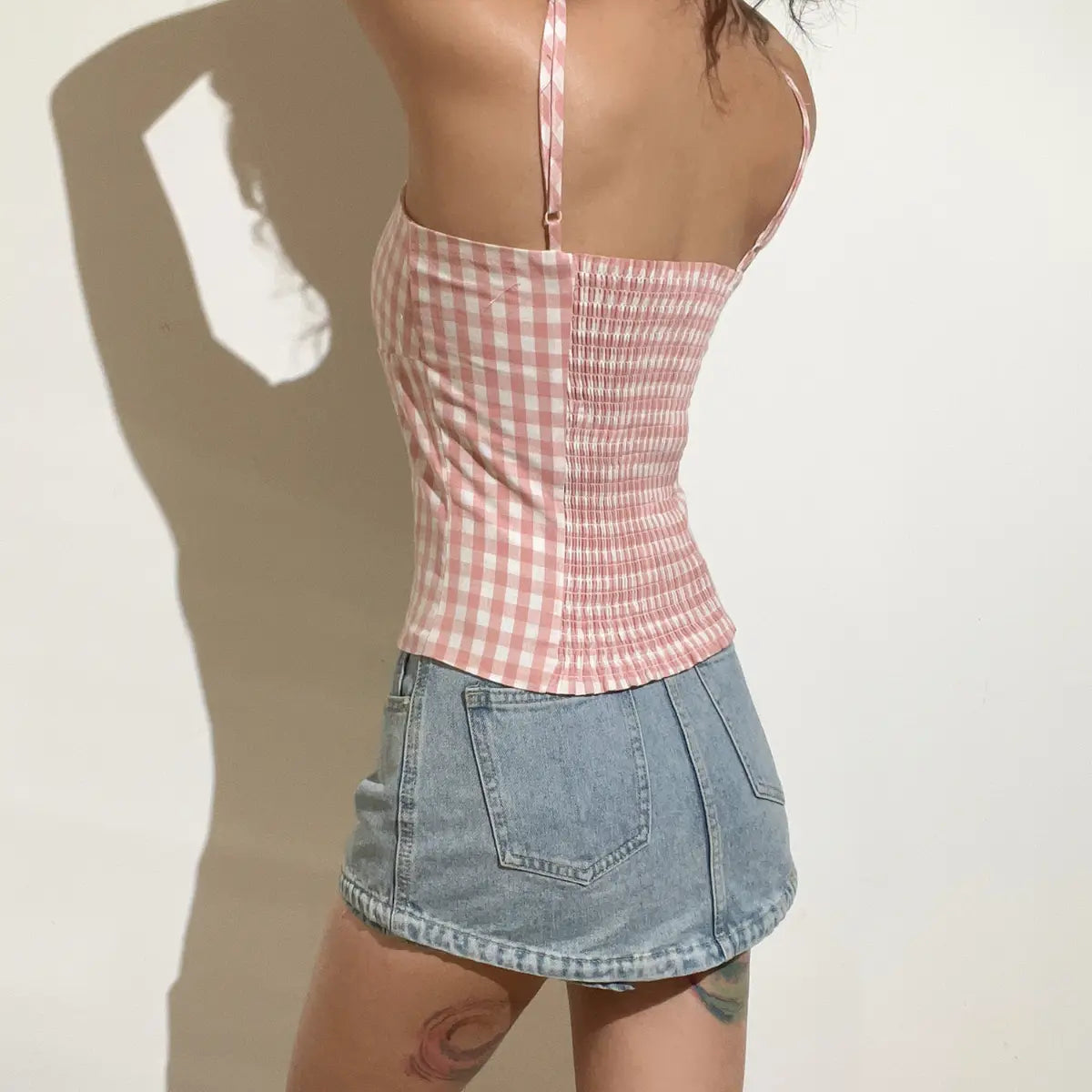 Back view of a pink and white gingham cami top, showing the smocked elastic panel and adjustable spaghetti straps.