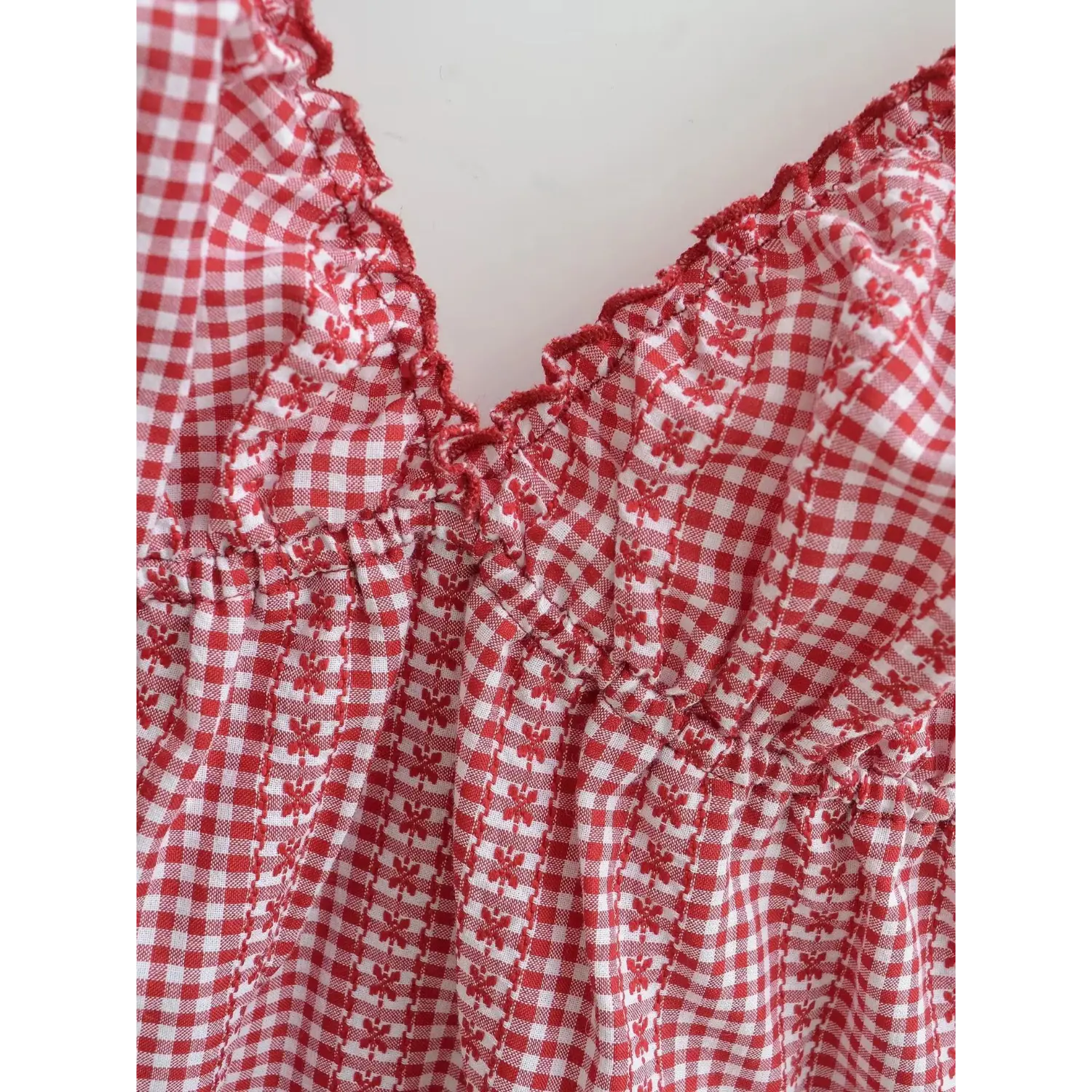 Red white floral gingham cami top neck close-up macro shot, scalloped lace edge bust gather woven check chiffon fabric stitching detail white background
