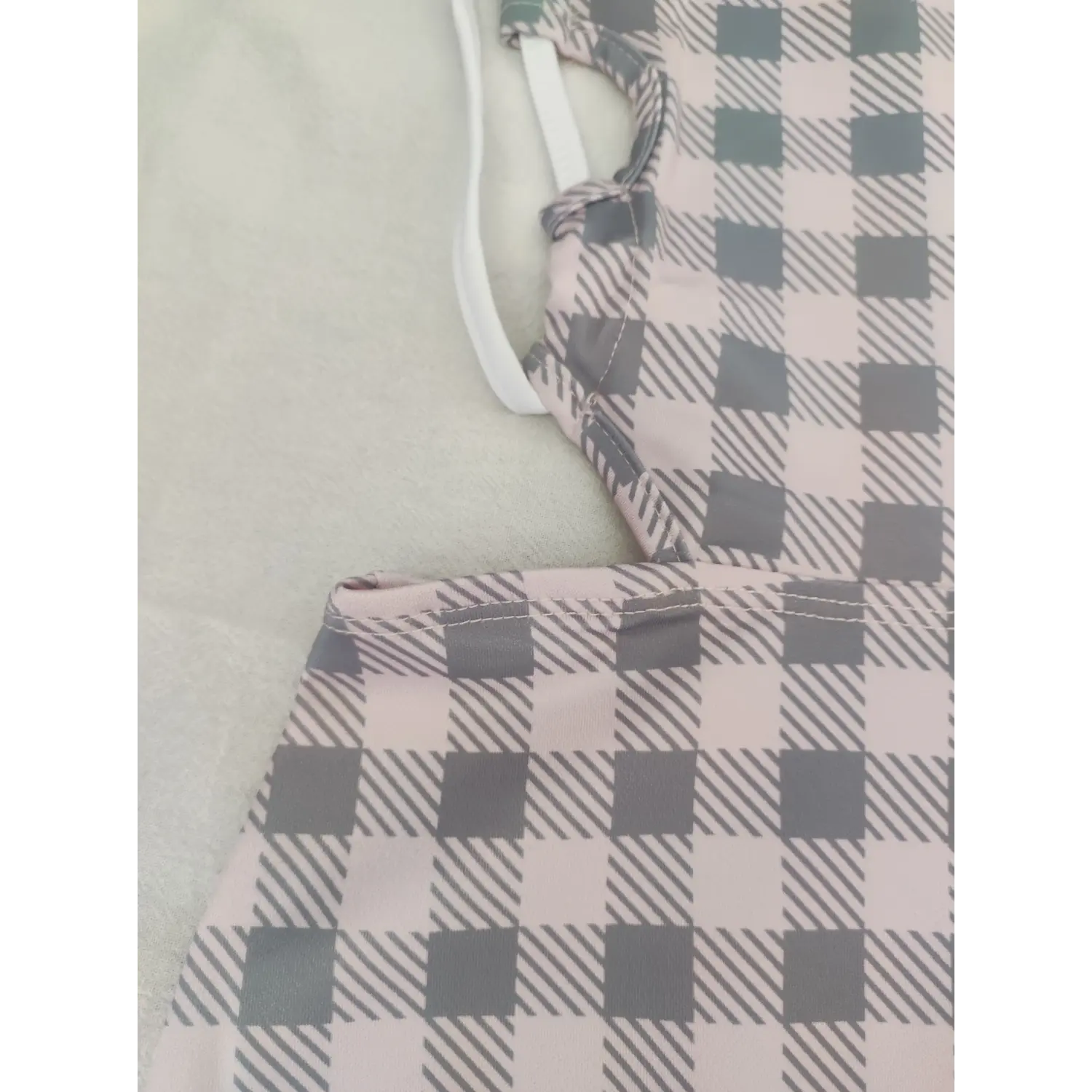 Closeup of white tie halter strap on pink grey gingham cutout dress