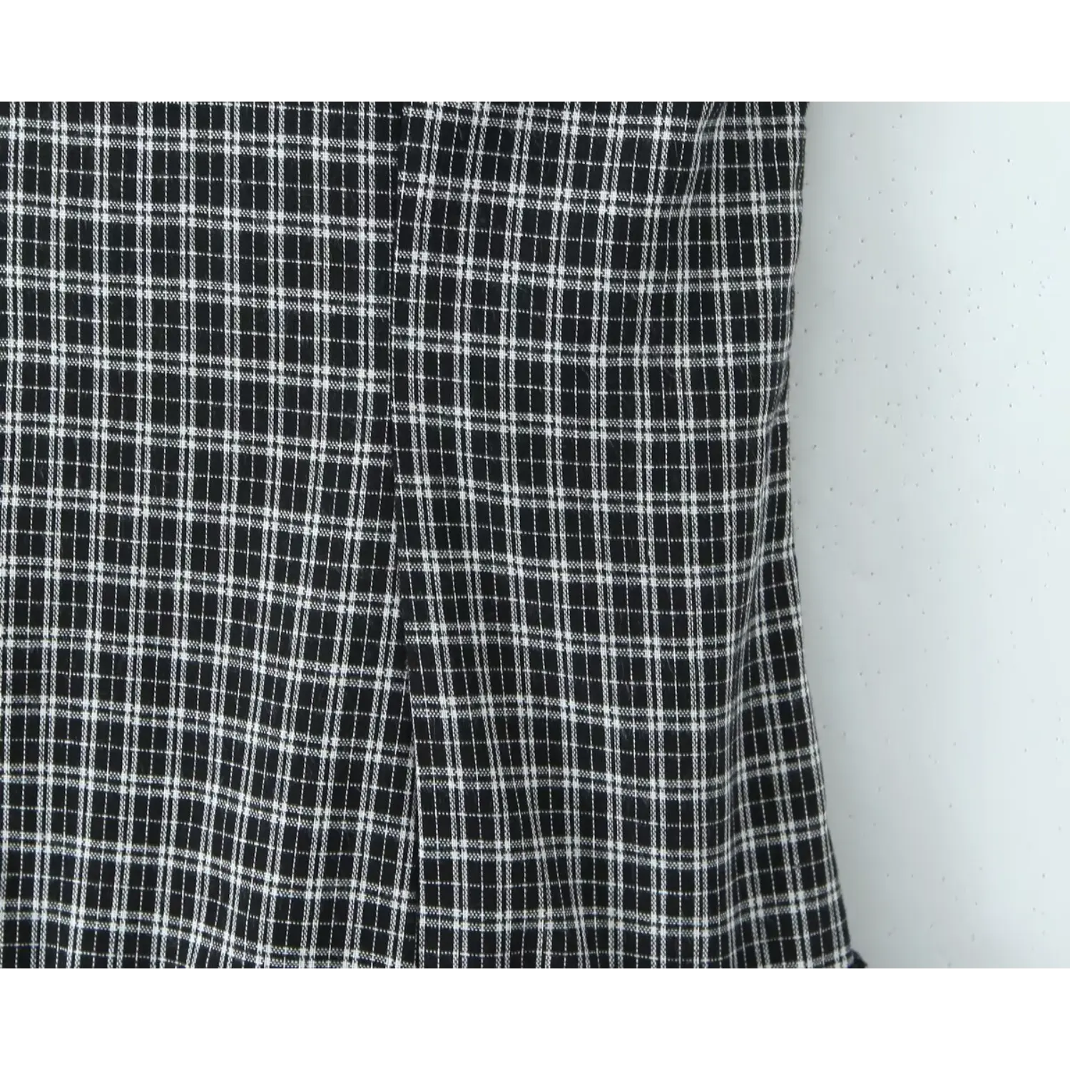Macro view of black‑white gingham woven fabric, vertical princess seam construction on dress bodice