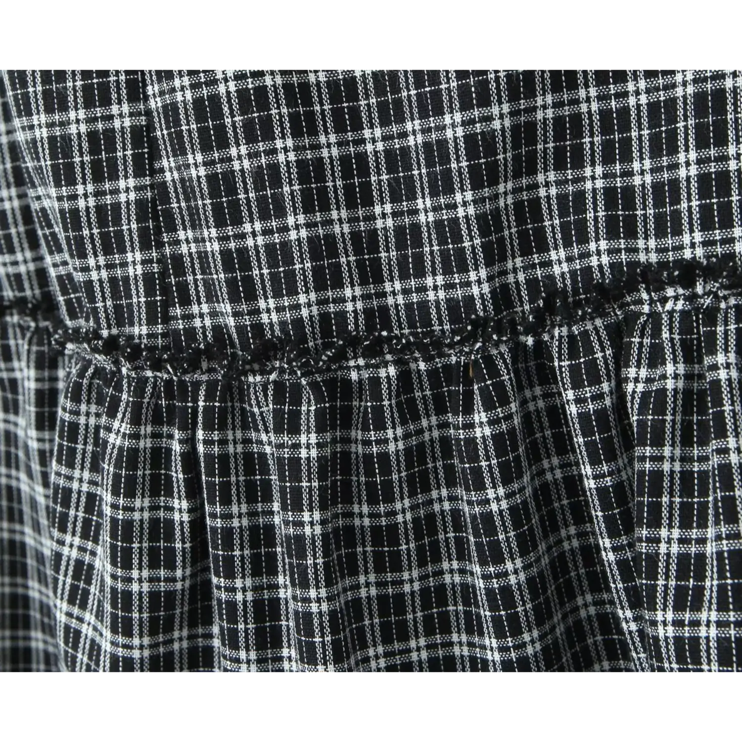 Close‑up tier connecting seam with black picot trim, gingham woven fabric texture on ruffle skirt