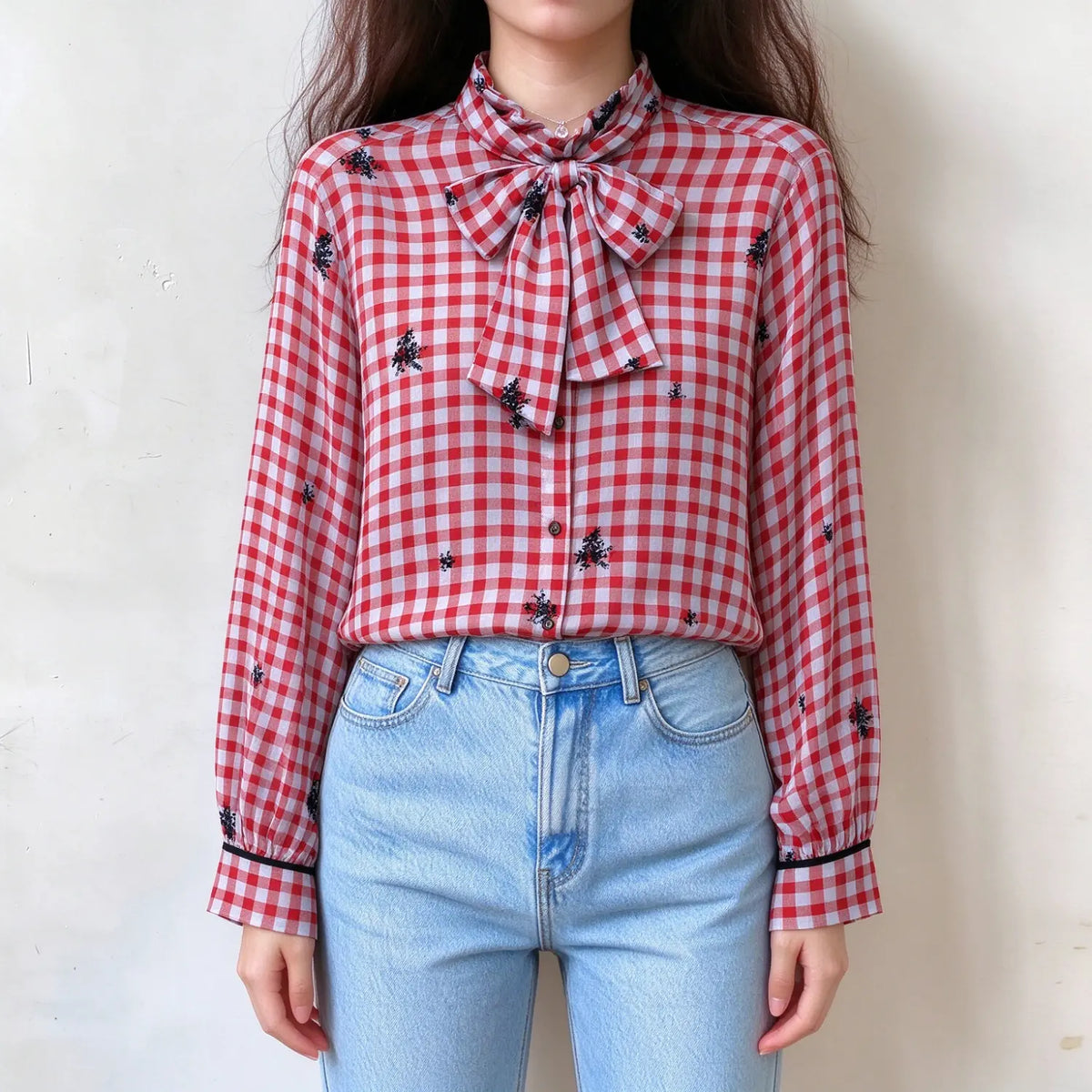 Model wearing gingham floral embroidered tie neck blouse, front view