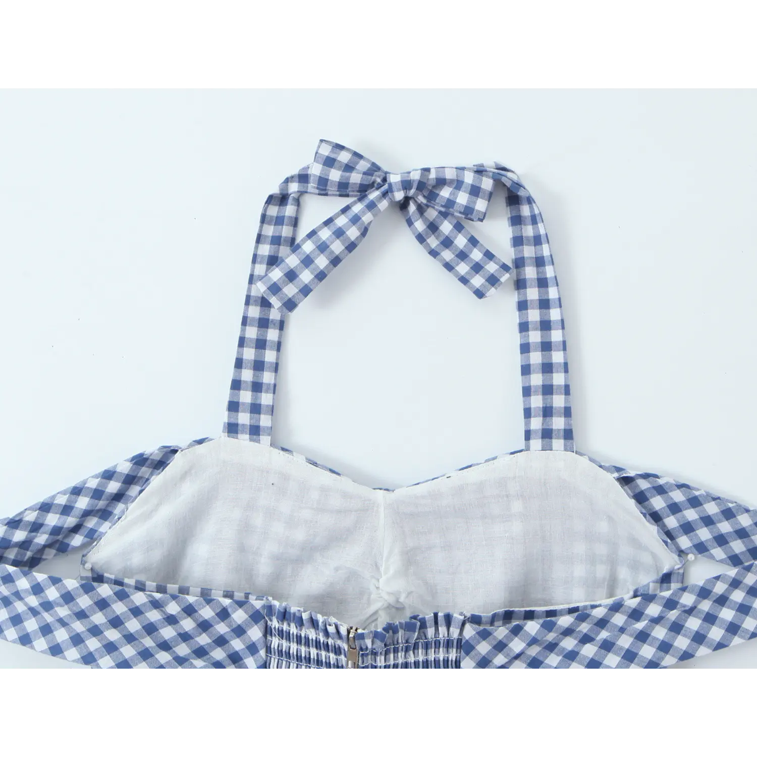 Blue gingham halter mini dress back inner lining tie bow close-up, matching wide gingham halter straps adjustable bow, full white bust lining elastic smocked panel with invisible zipper non-sheer inner construction shot