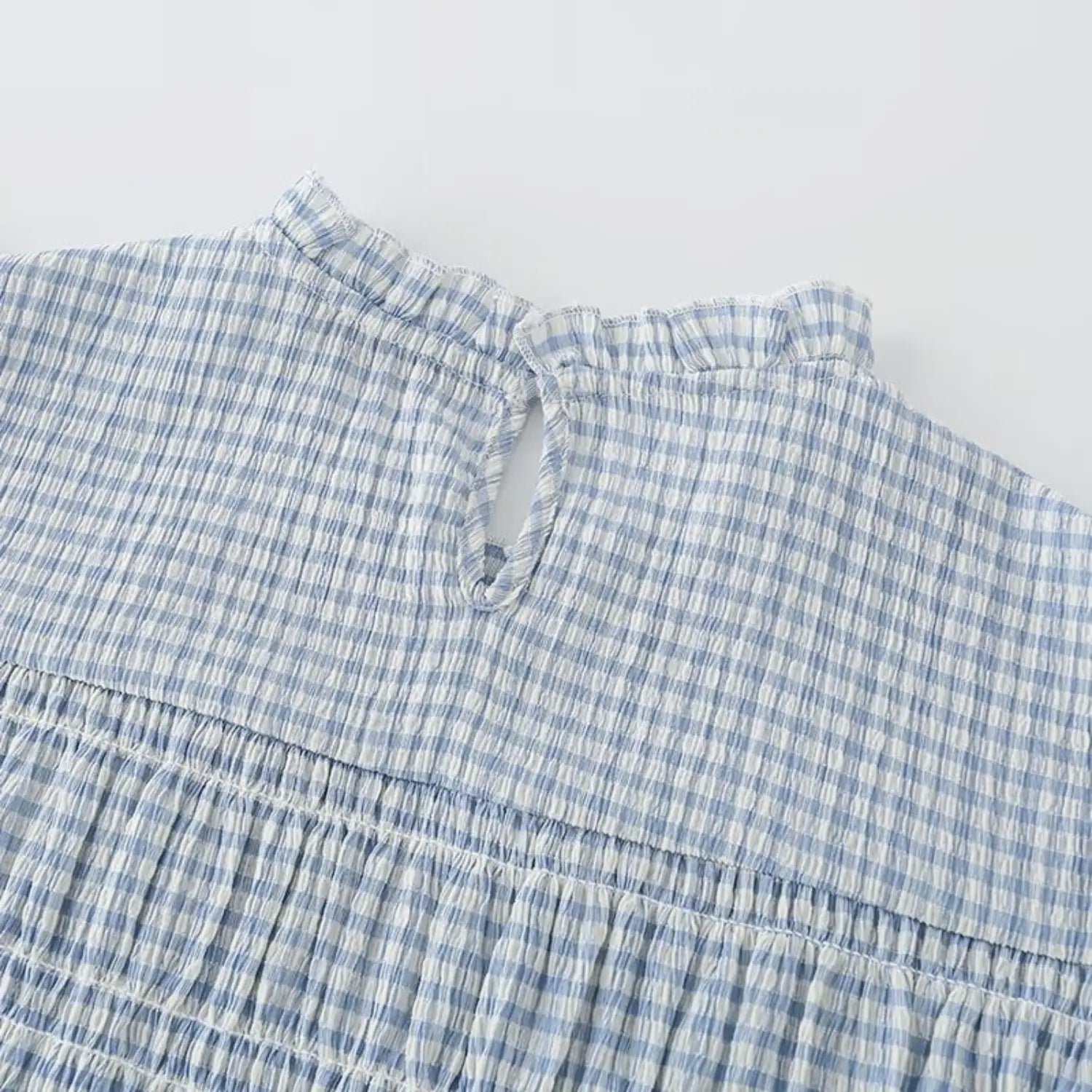 Back ruffle mock neck closeup, back keyhole cutout with single button closure, frilled collar edge, full gingham smocked upper back