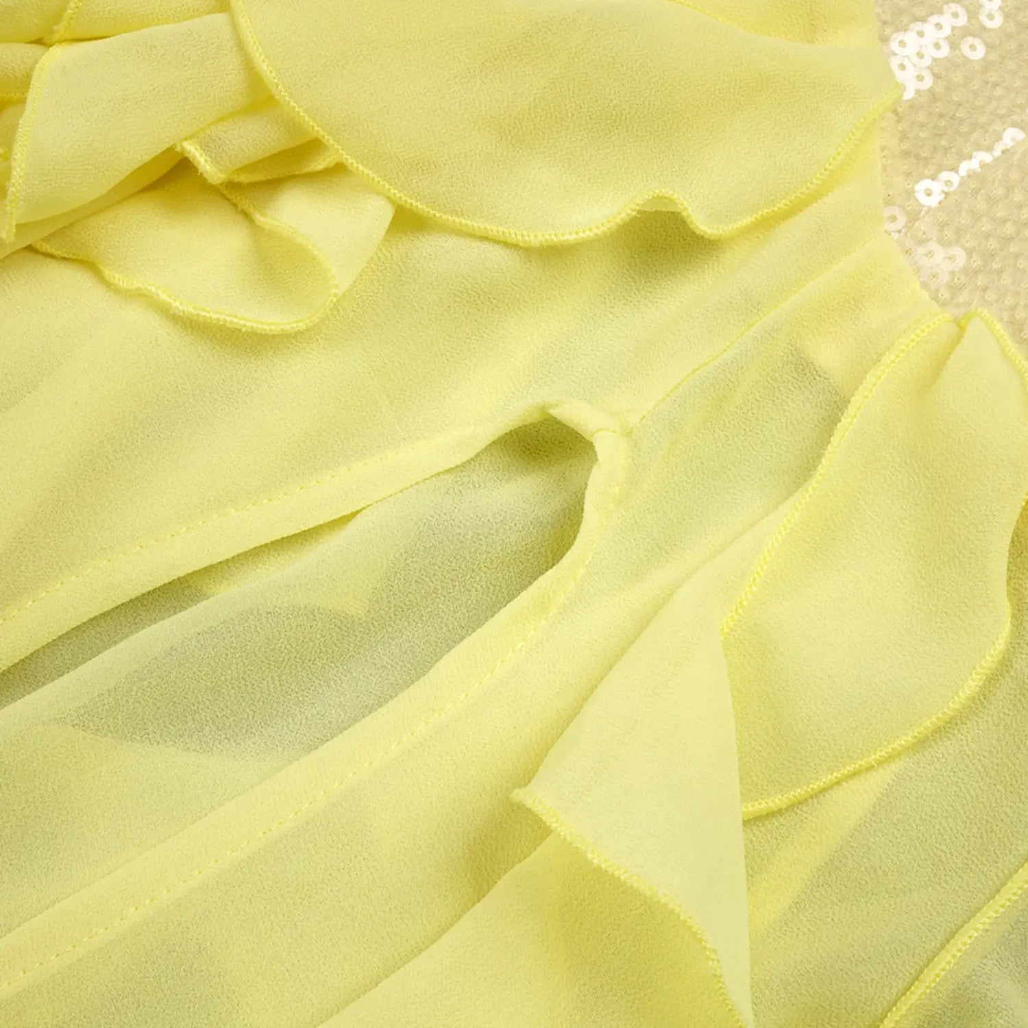 Partial shot of side high slit on yellow evening gown, overlapping sheer chiffon ruffles showing semi-transparent lightweight texture