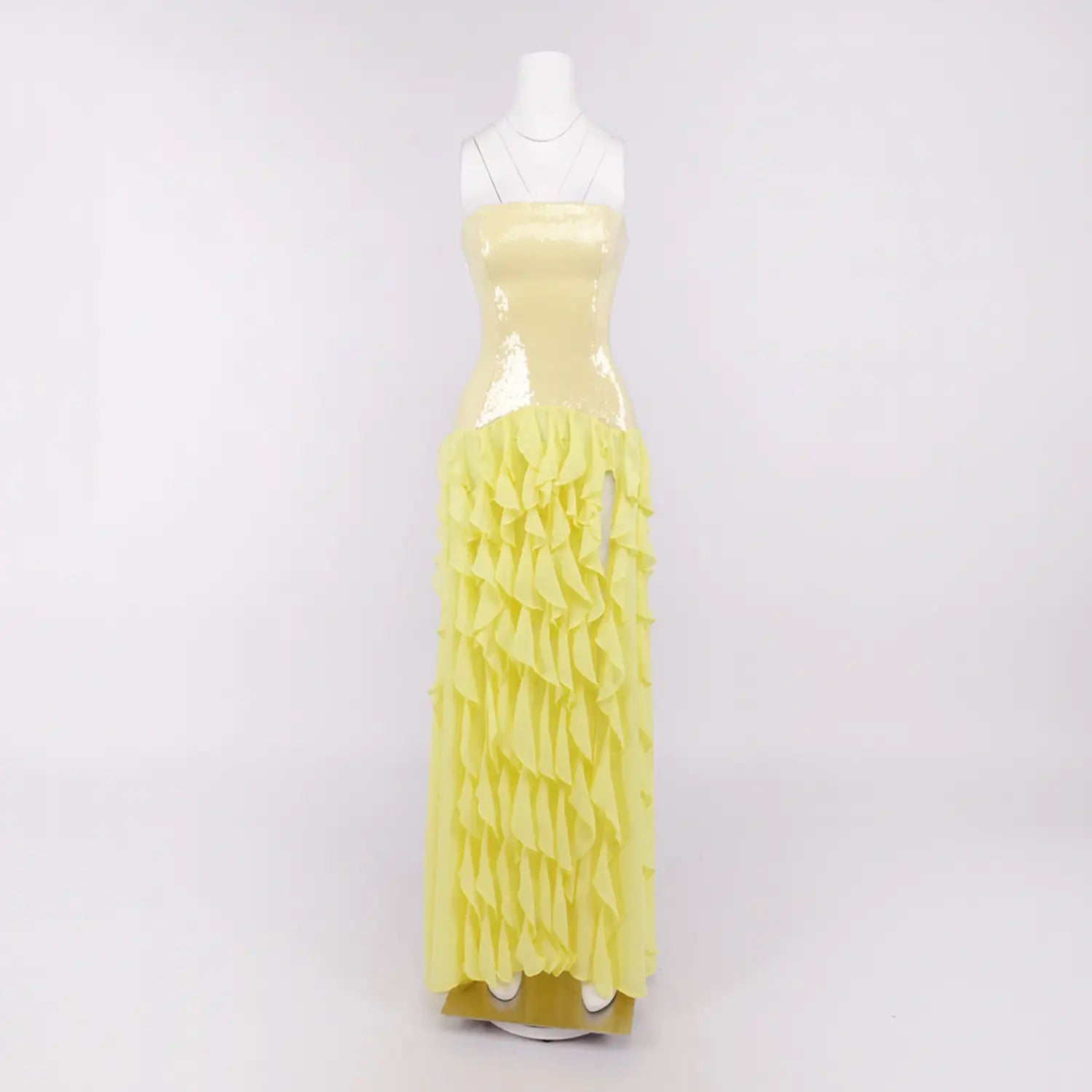 White background mannequin shot of yellow strapless evening maxi gown, fitted sequin bust, layered ruffled chiffon skirt with side high slit for party formal wear