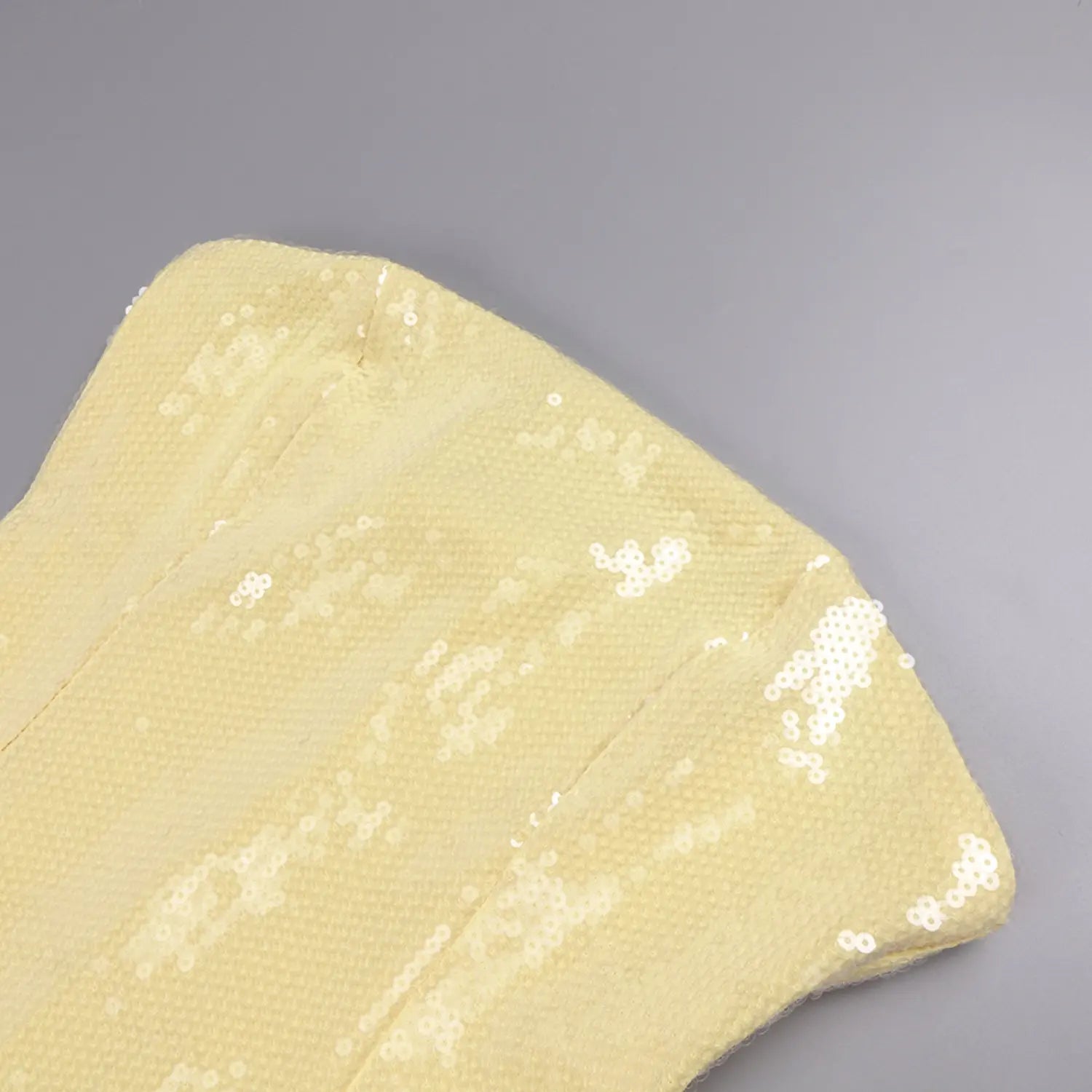 Macro close-up of yellow sequin mesh bodice fabric, scattered reflective white sequins woven on textured stretch base for strapless formal gown