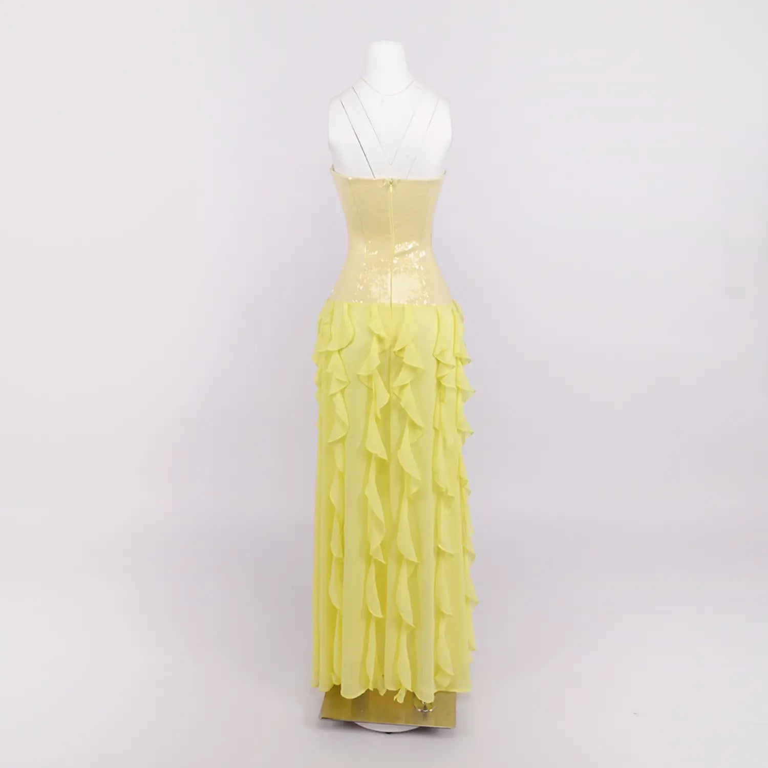 White background full back mannequin shot of yellow evening maxi dress, fitted sequin corset, cascading tiered chiffon ruffles and center back hidden zipper