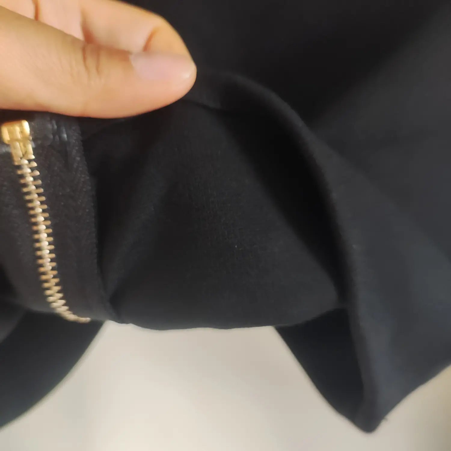 Close up inner fabric and gold metal zipper detail of black crossover long sleeve crop top