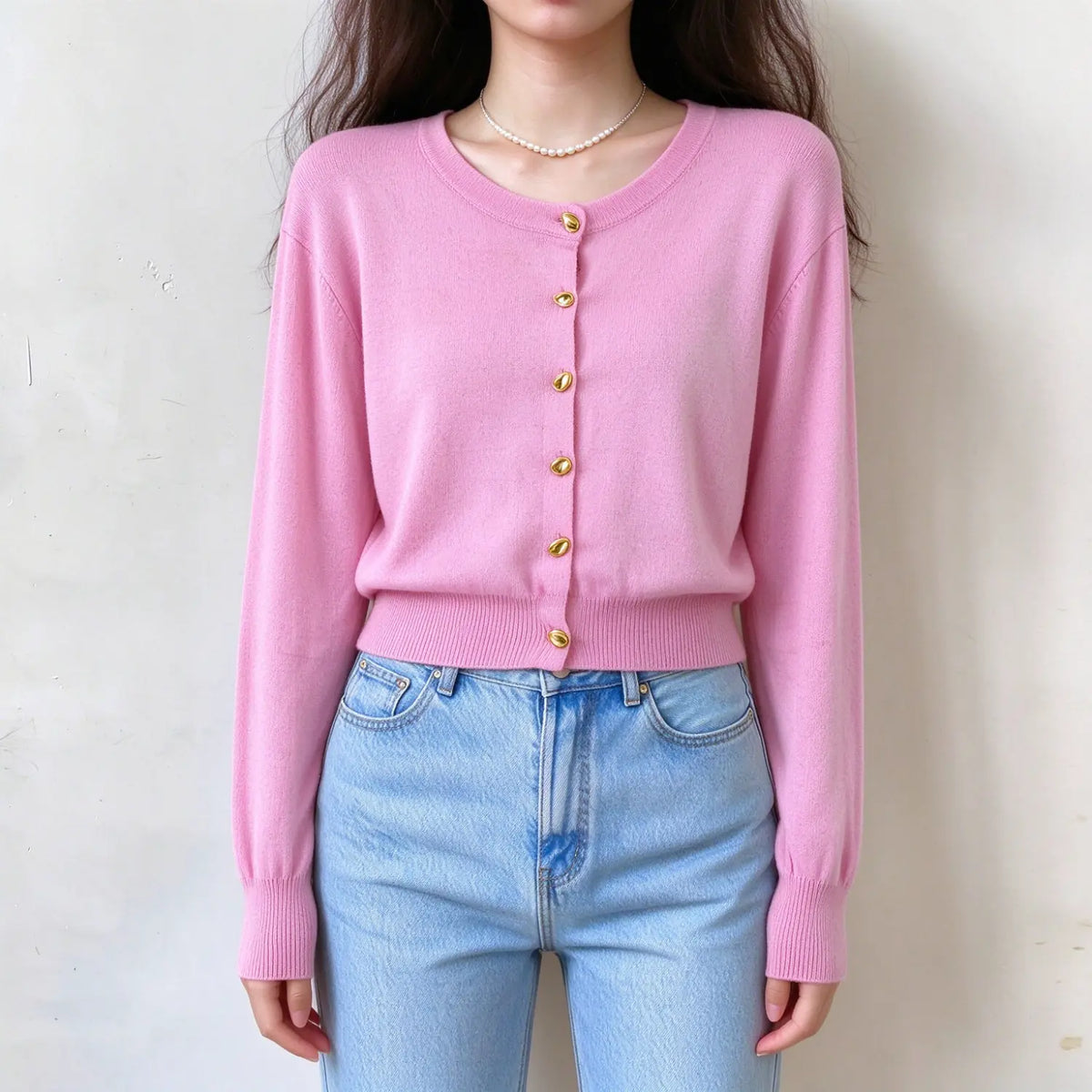 Model wearing gold button round neck cropped cardigan in pink, front view