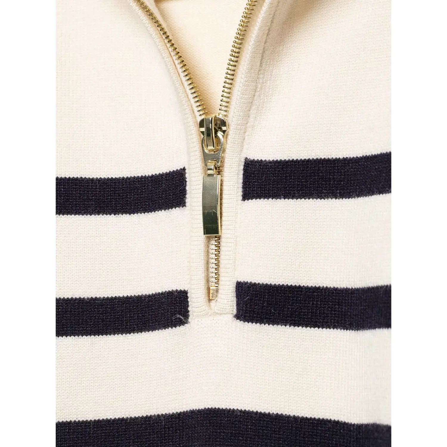 Macro close‑up of gold metal half‑zip zipper on cream navy striped knit sweater