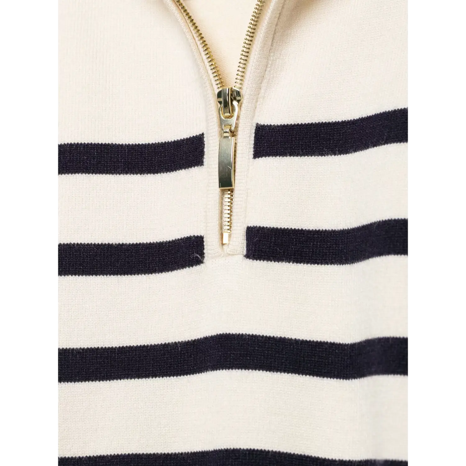 Extreme close‑up of gold half‑zip zipper hardware against striped knit fabric