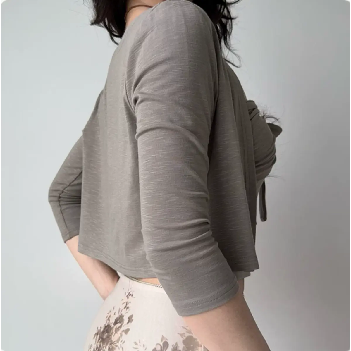 Back view of a light gray cropped cardigan paired with a matching bow-front tube top.