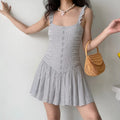 Model wearing a gray lace cami mini dress, showcasing the ruffled straps, ruched bodice, and flowy gathered skirt.