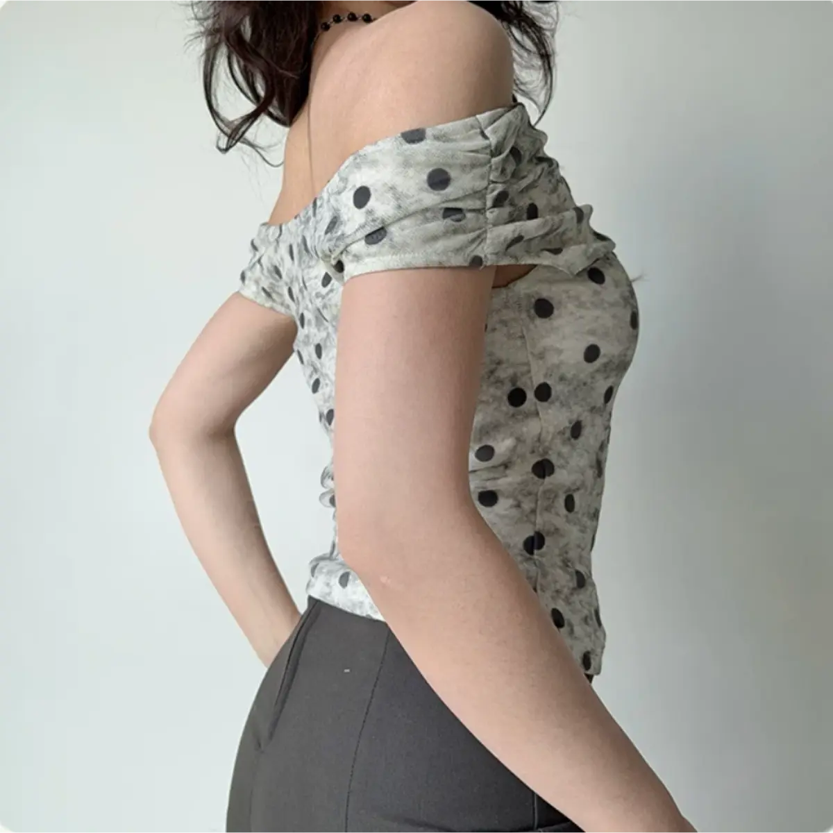 Back view of a gray and black polka dot off-the-shoulder top, paired with a gray midi skirt.