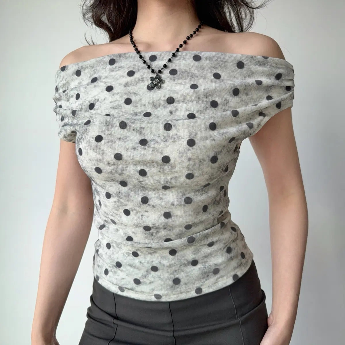 The top styled with a black beaded flower necklace, highlighting the neckline.