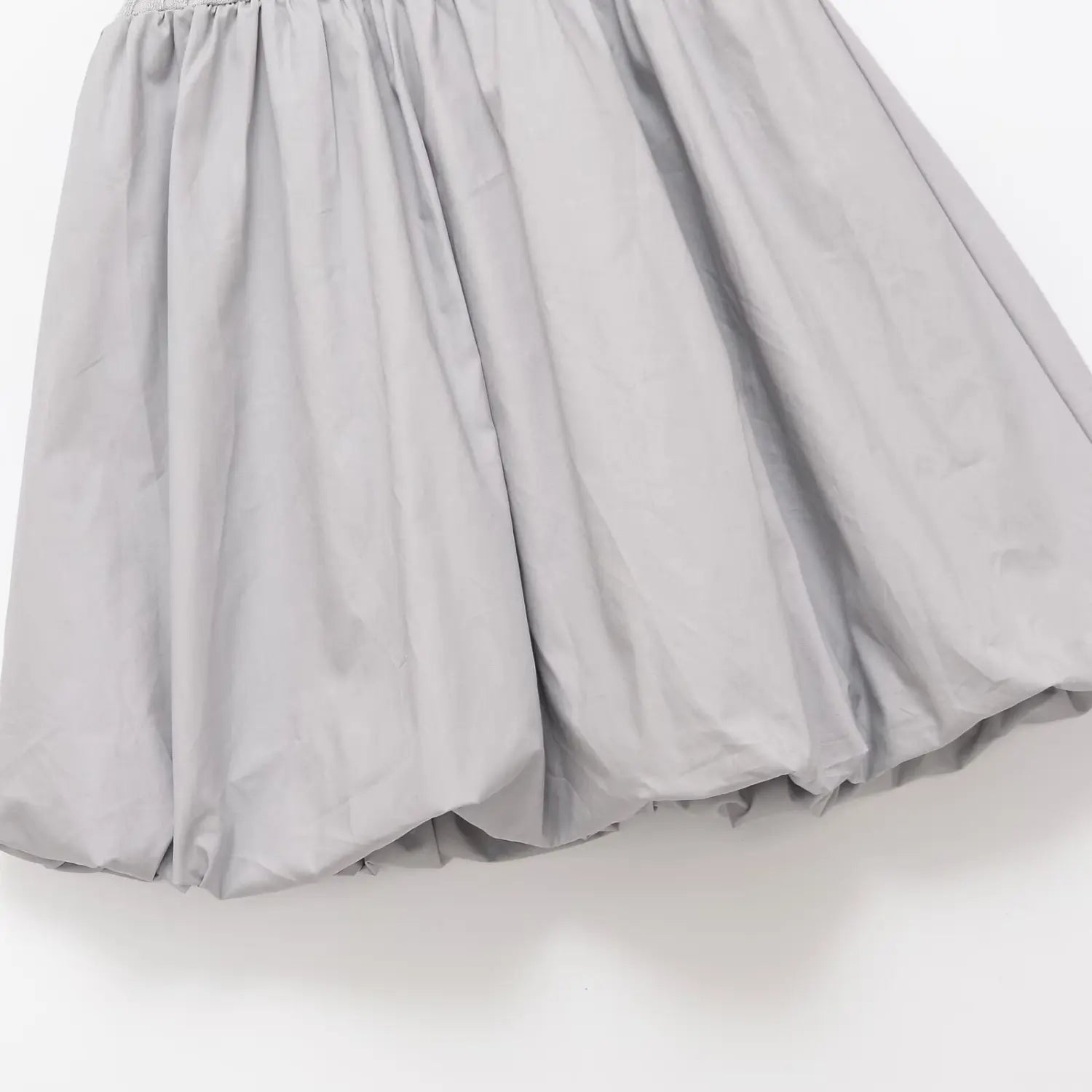 Close-up of the gathered bubble hem made of poplin fabric on the gray knit dress