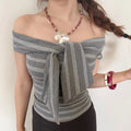 Close-up view of a woman wearing a gray striped off-shoulder top with a large bow detail, showing the neckline and striped pattern.