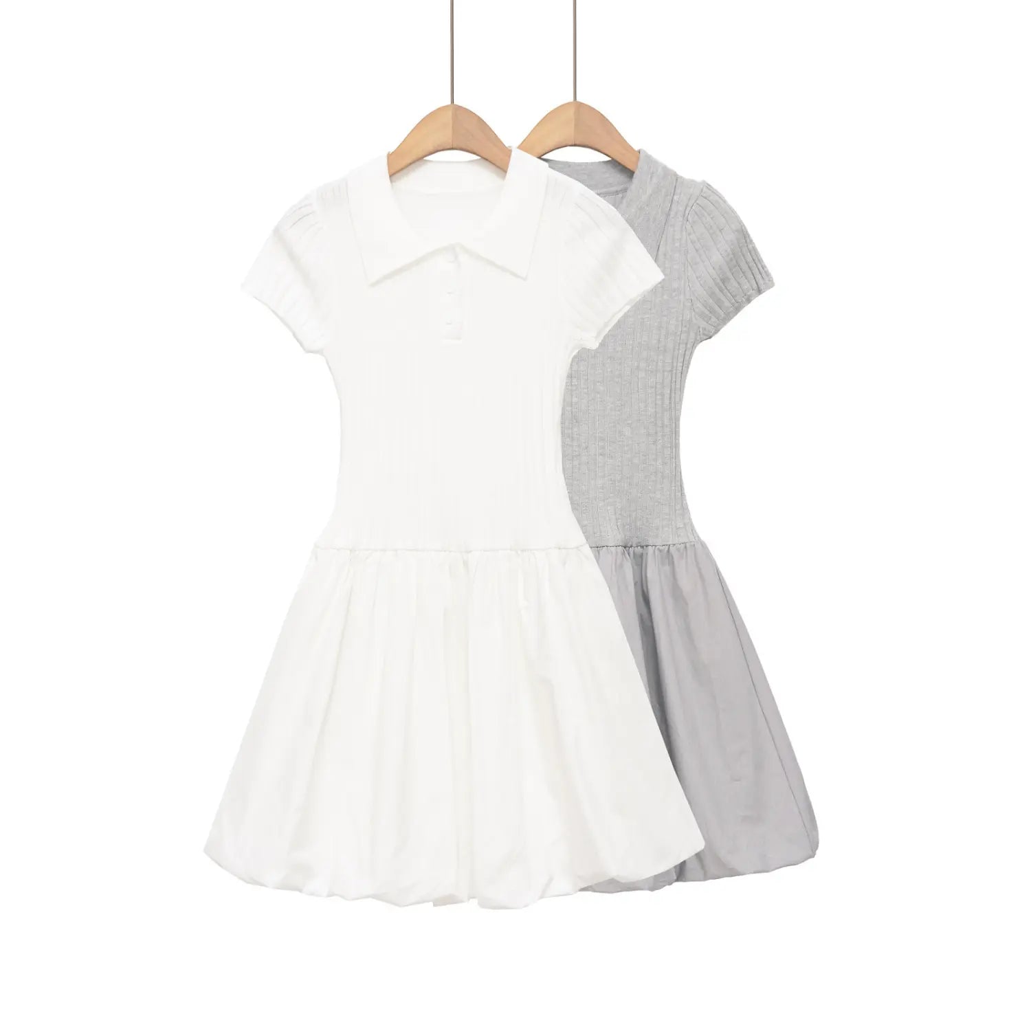 Full view of two-tone polo-collar knit dresses (white and light gray) with balloon hems hanging on wooden hangers