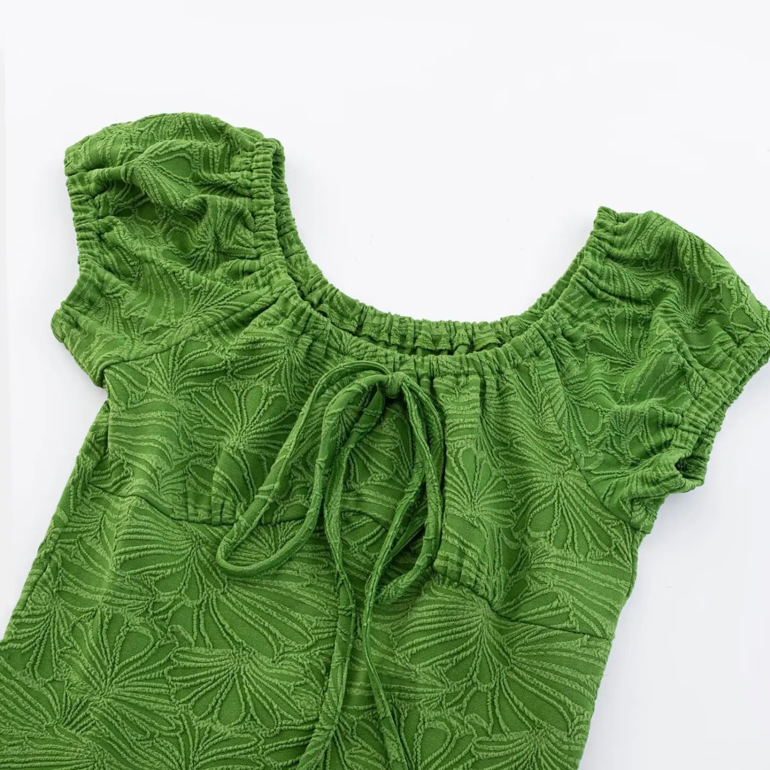 Close flat detail shot of front bust self-fabric drawstring tie on green jacquard mini dress, elastic gathered square neck and raised leaf emboss texture