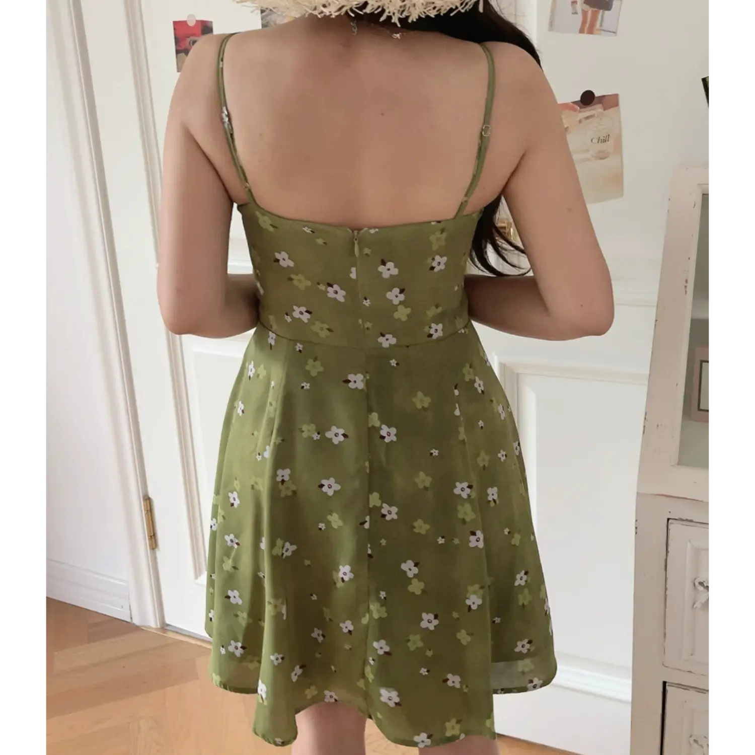 Avocado green tiny floral cami mini dress full back model shot, adjustable printed thin straps invisible back zipper, white door home indoor outfit photo