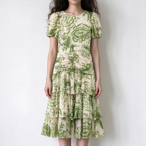 Model wearing green floral chiffon maxi dress, round neck, puff short sleeves, front ruched waist, tiered ruffle maxi skirt, white backdrop