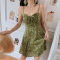 Avocado green tiny floral drawstring cami mini dress half body vibe shot, gathered bust loose flared skirt, model hand in pocket soft korean indoor outfit