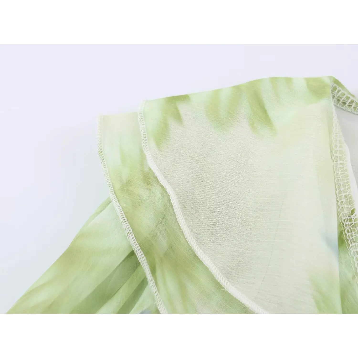 Macro close‑up of lightweight semi‑sheer chiffon fabric and ruffle edge stitching of green floral maxi dress