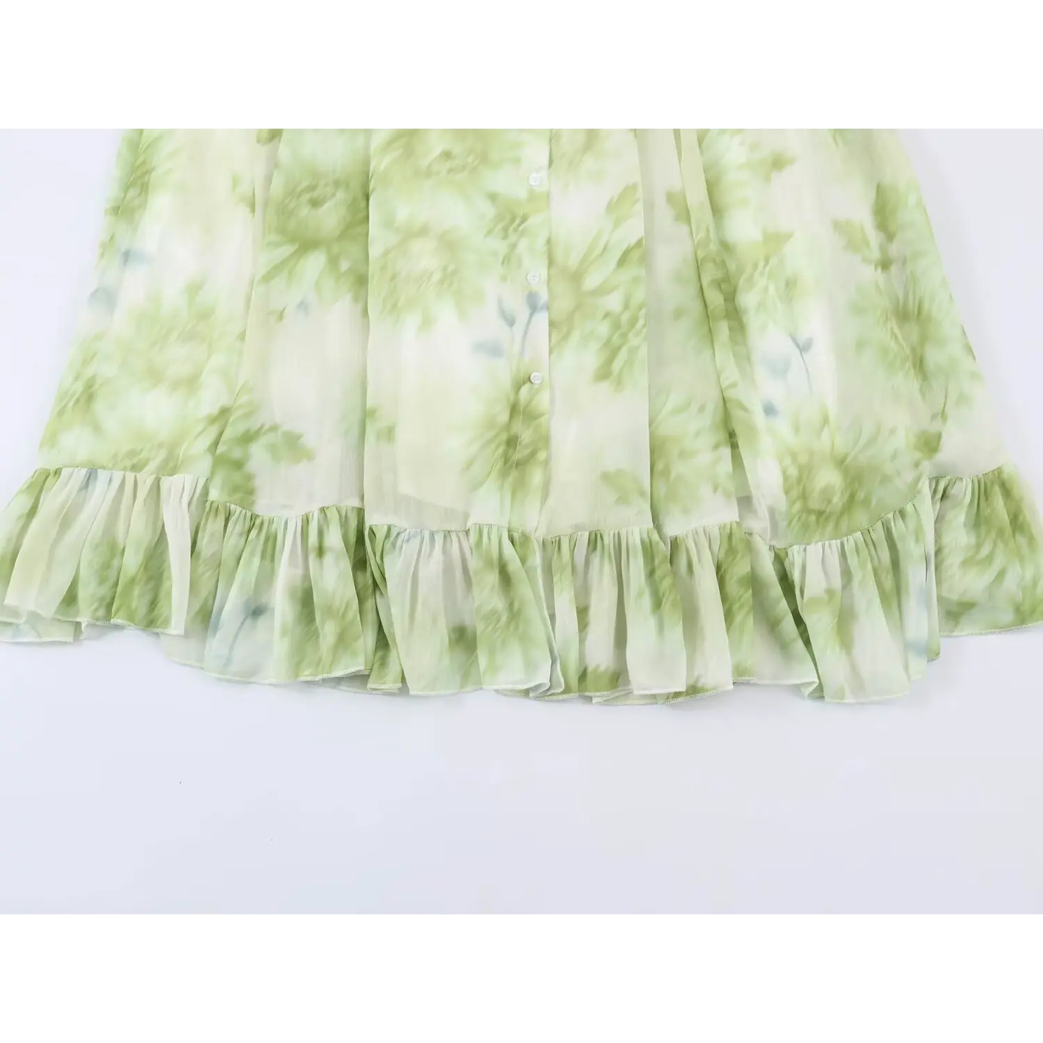 Full partial shot of skirt ruffle hem, front button placket on green floral maxi dress