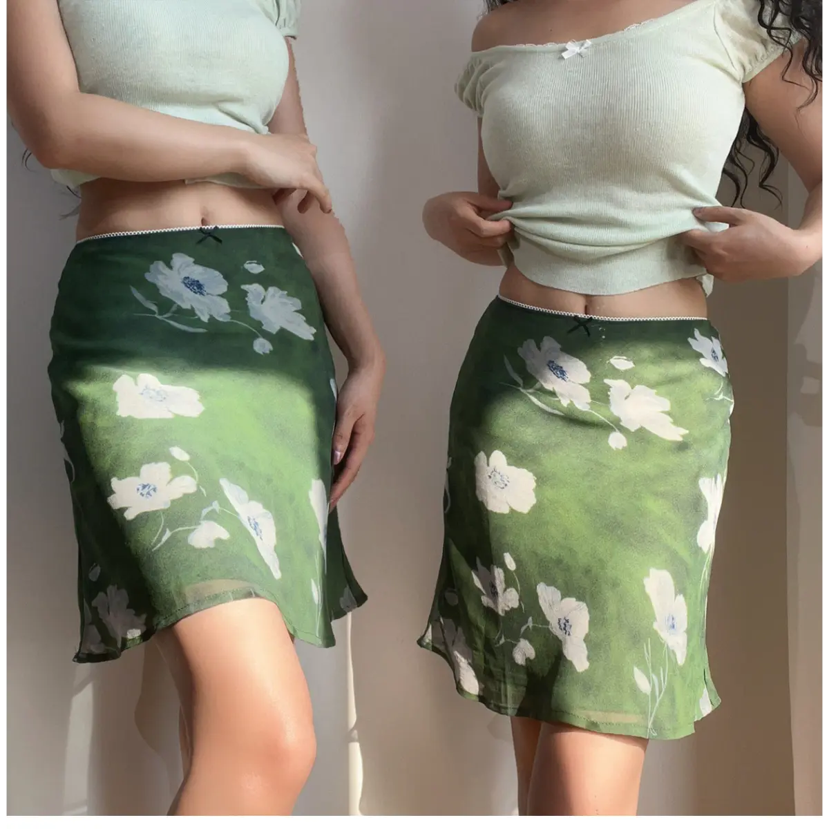  Two models wearing a green floral chiffon mini skirt with white flowers, showing different styling options with a light green cropped top.