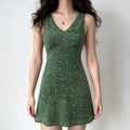 Full-body shot of a woman wearing a green floral print sleeveless V-neck mini dress.