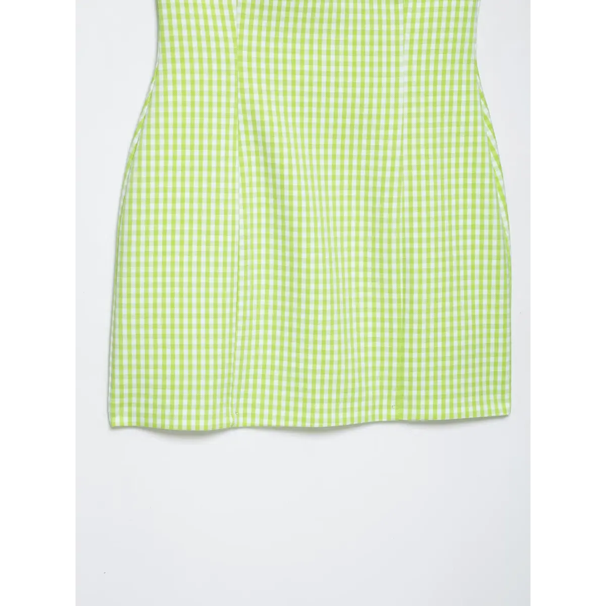 Close-up of the hem of a green gingham halter dress, showing the clean, straight-cut finish.