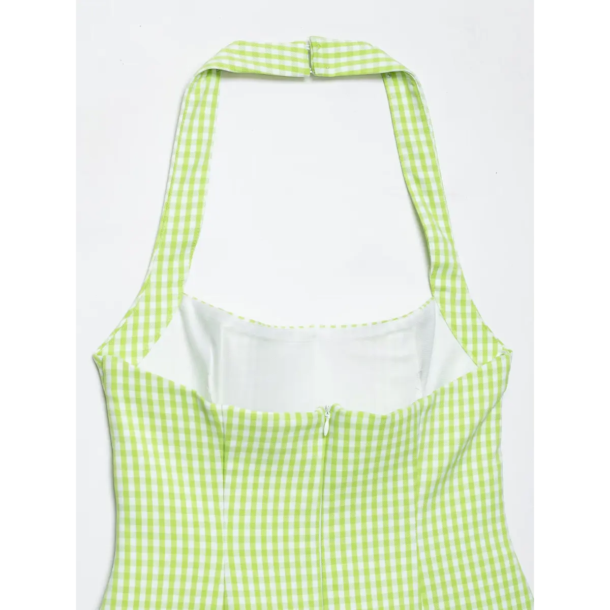 Close-up back view of a green and white gingham halter dress, showing the halter neckline, inner lining, and back zipper closure.
