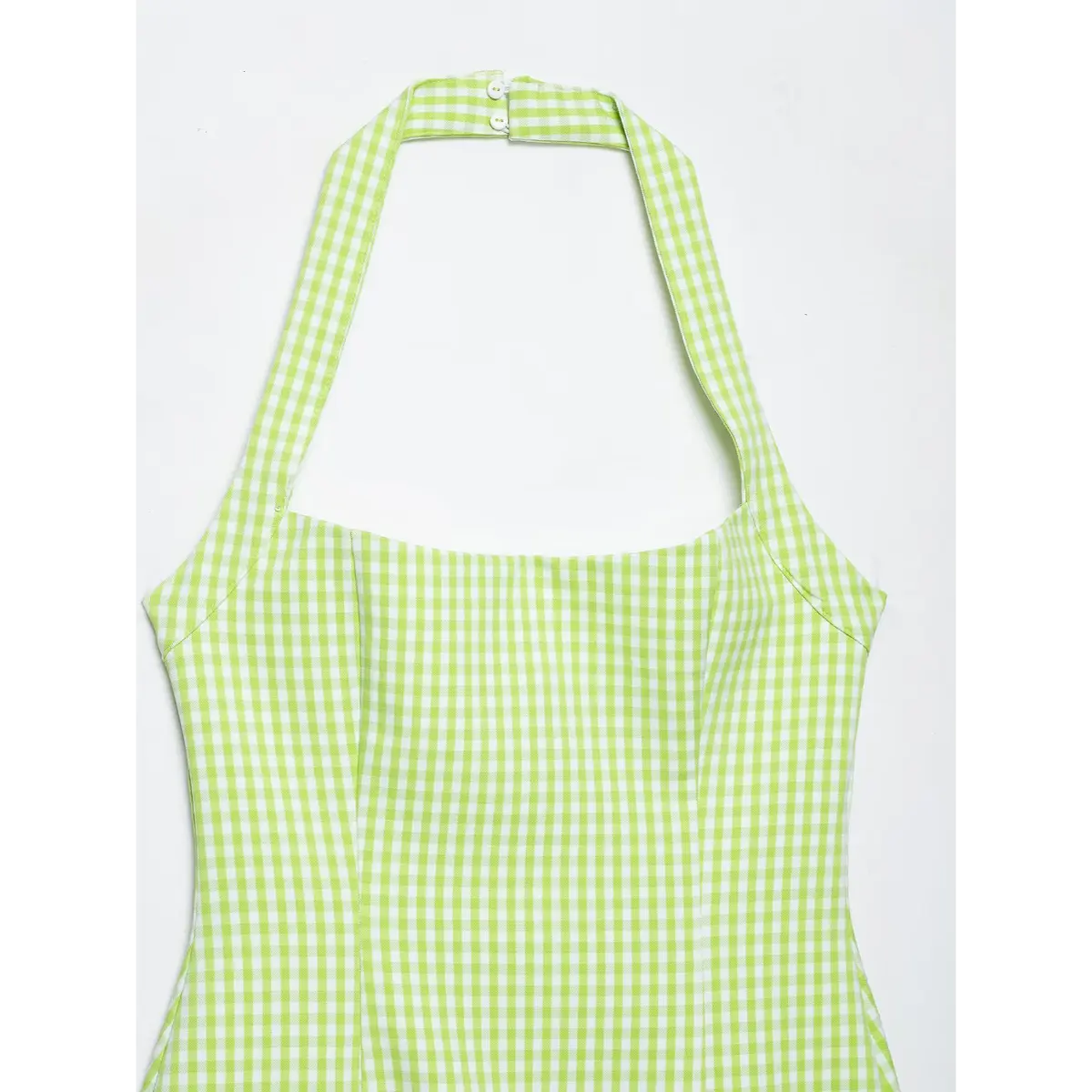Close-up front view of a green and white gingham halter dress, showing the square neckline and halter strap buttons.